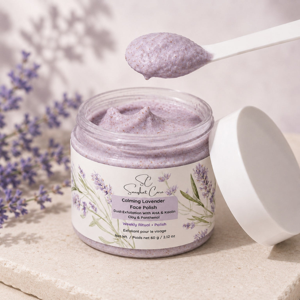 Calming Lavender Face Polish creamy lavender exfoliating texture on a scoop above the open jar
